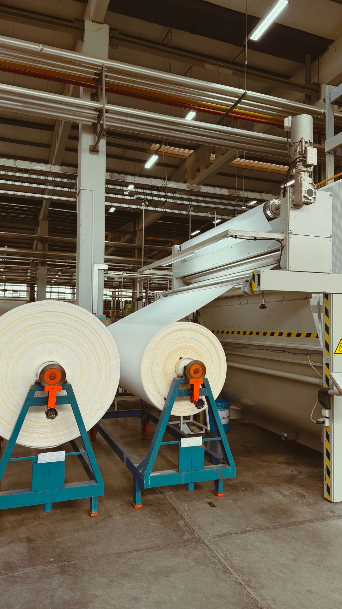 Material rolls feeding a PVC coating line inside a textile manufacturing facility